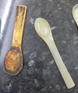 An unpolished spoon next to a finished one