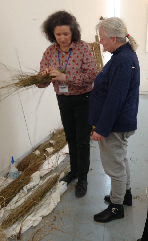 Caroline showing a participant how to make rope with different materials.