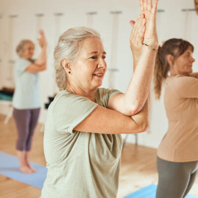 Group of people practicing yoga in a studio, standing on mats with arms crossed in an eagle pose.
