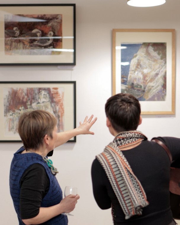 An artist showing off her artwork at an open evening.