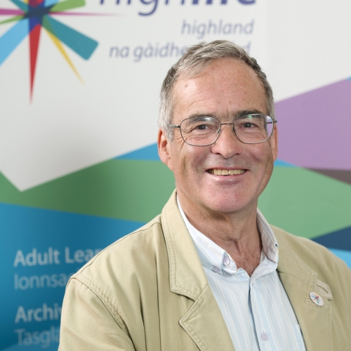 A man in a yellow suit smiles at the camera
