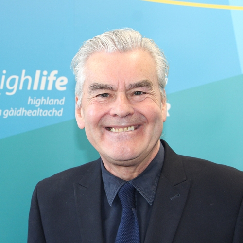 A man with grey hair smiles at the camera