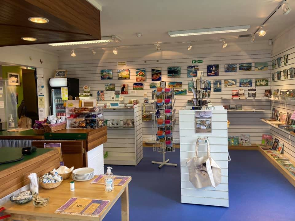 Gift shop area with shelves and display stands holding postcards, books, and souvenirs.