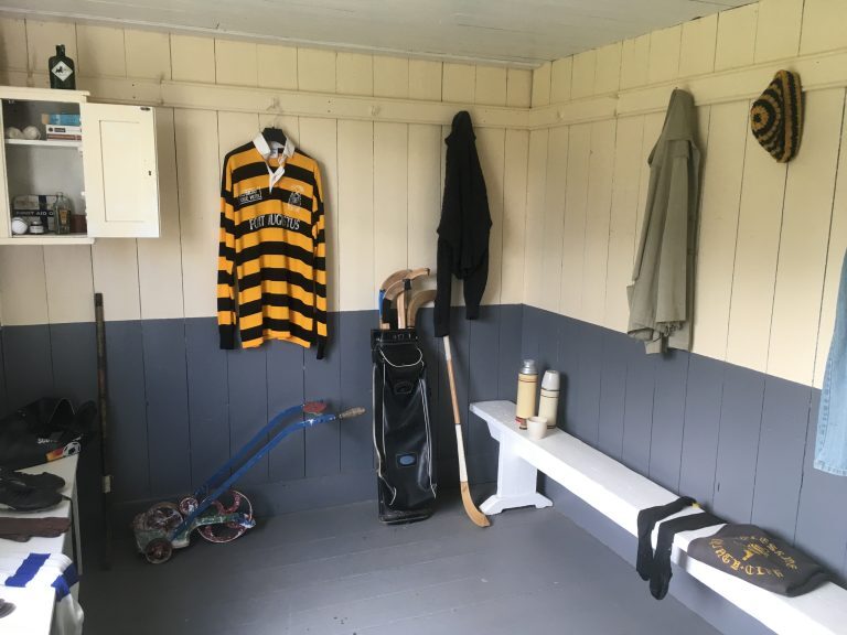 Inside the Boleskine pavilion changing room, showing jerseys, camans, benches, flasks and sporting equipment.