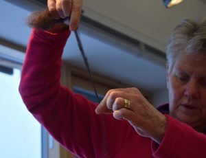 A person holding a length of spun yarn between their hands.