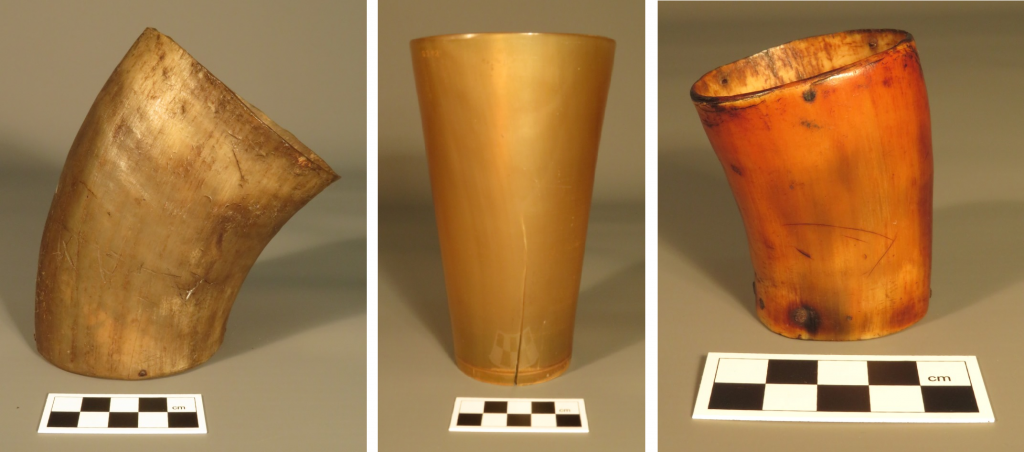 Three horn tumblers of different shapes and colours displayed beside a measurement scale.
