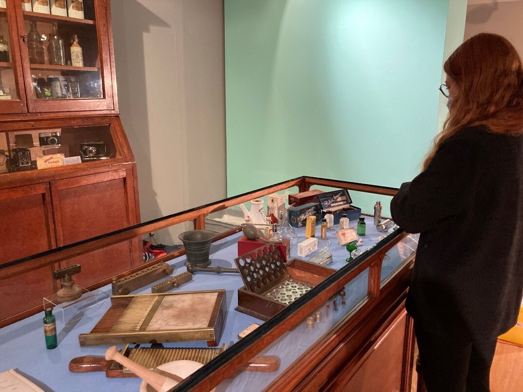 A person arranging small historic medical objects inside a glass display case in a museum gallery.