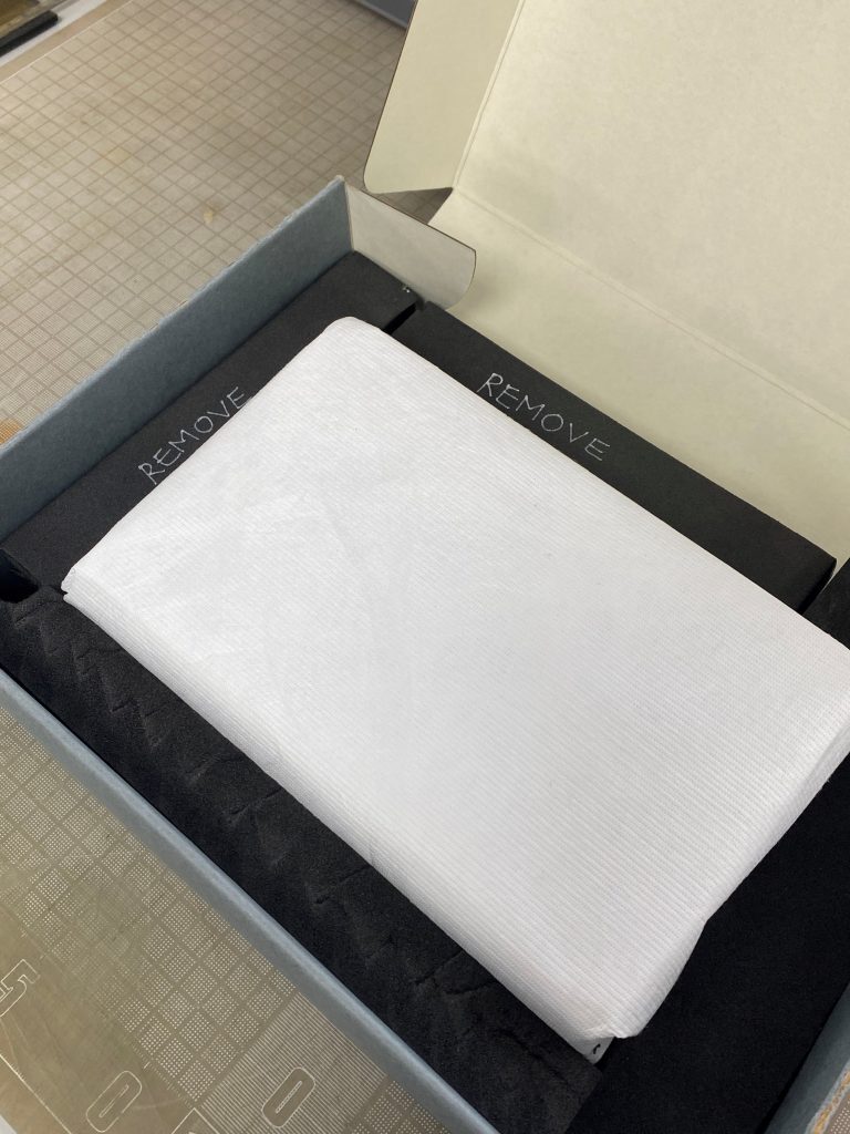 A book wrapped in white Tyvek fabric, placed in a padded storage box ready for transport.