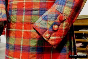 A detailed view of a tartan jacket sleeve cuff featuring matching fabric‑covered buttons.