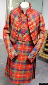 A matching tartan jacket and skirt displayed on a mannequin in a museum setting.