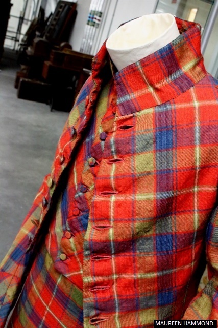 A side‑angled view of a tartan jacket and waistcoat on a mannequin, highlighting the front buttons and fitted cut.