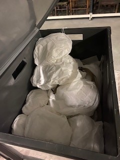 A large dark storage box filled with several museum objects wrapped in white tissue for protection.
