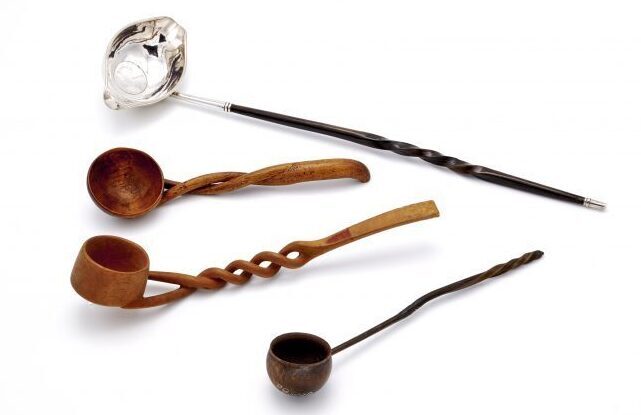 Three wooden spoons and a silver spoon on a white background