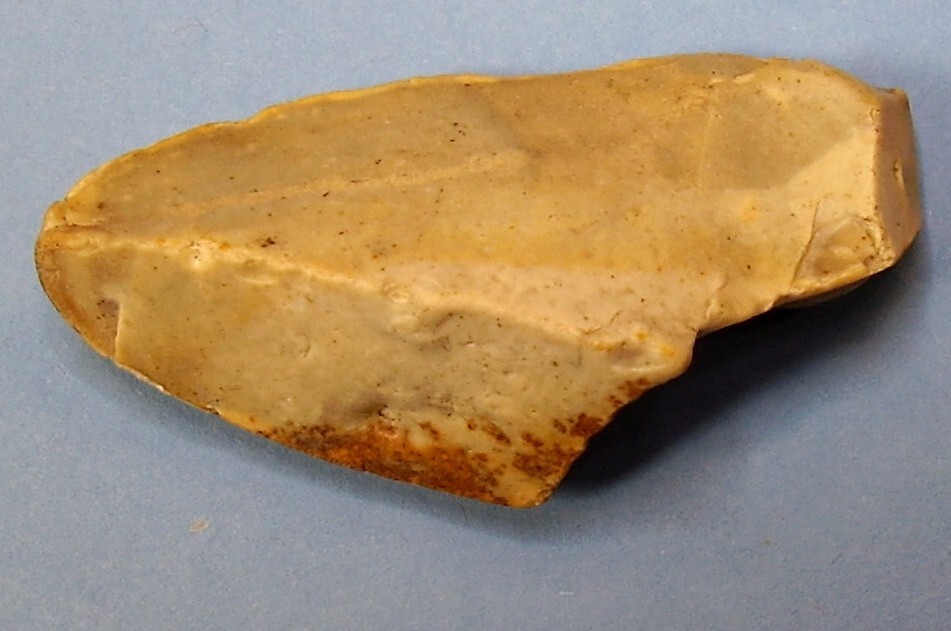 A piece of stone shaped to have sharp edges in a triangular shape on a blue background.