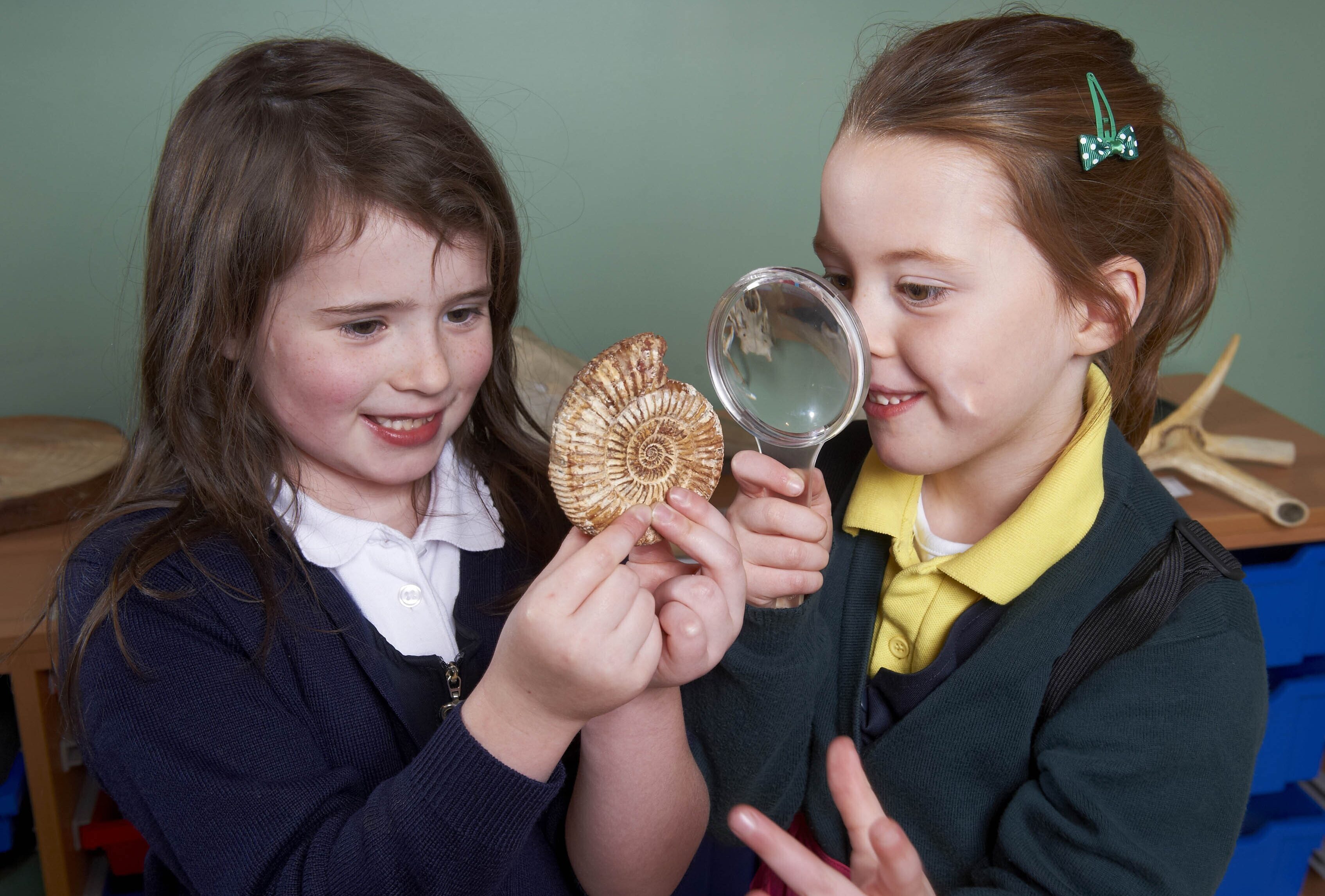 Two girls looking at a fossil through a magnifying glass