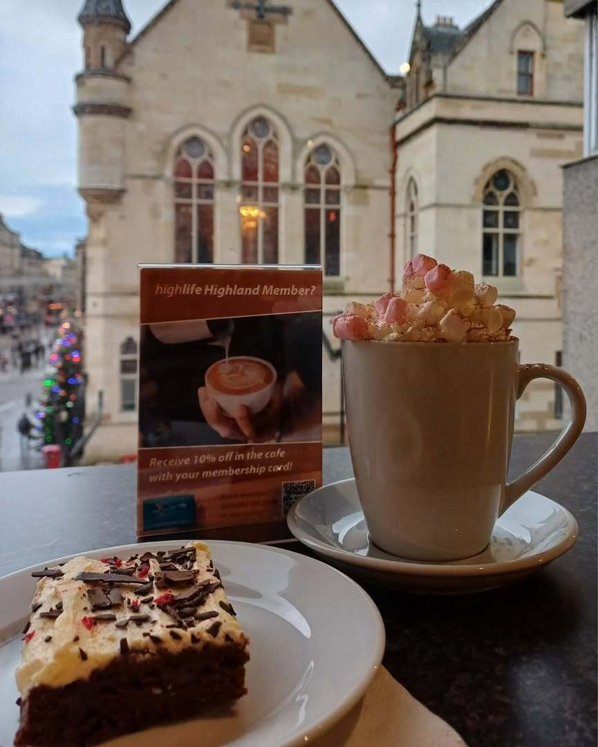 A hot chocolate in a mug with marshmallows and a chocolate brownie on a plate