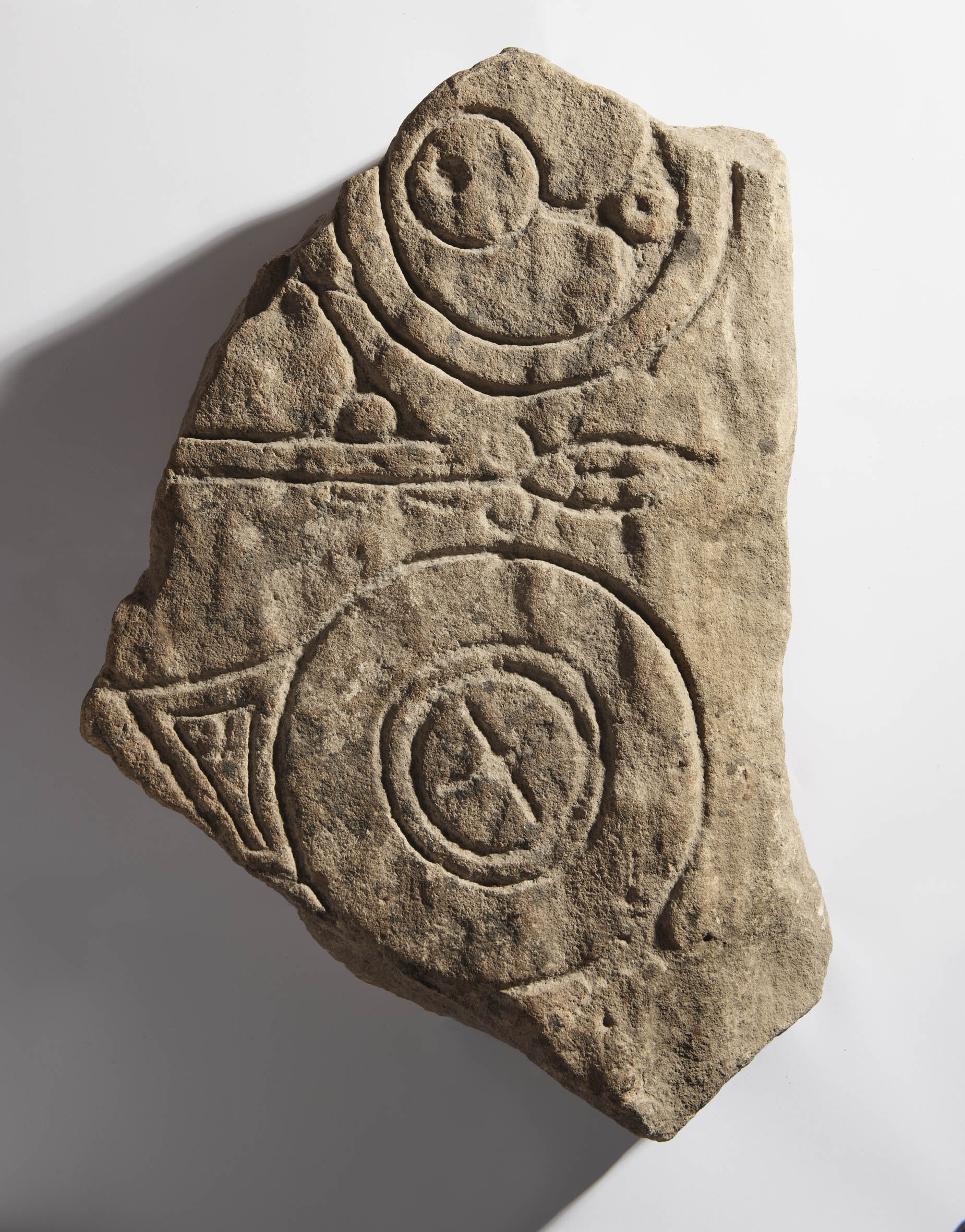Fragment of a Pictish symbol stone found at Torgorm, showing part of a geometric symbol of circles and a spear shape, carved into stone.