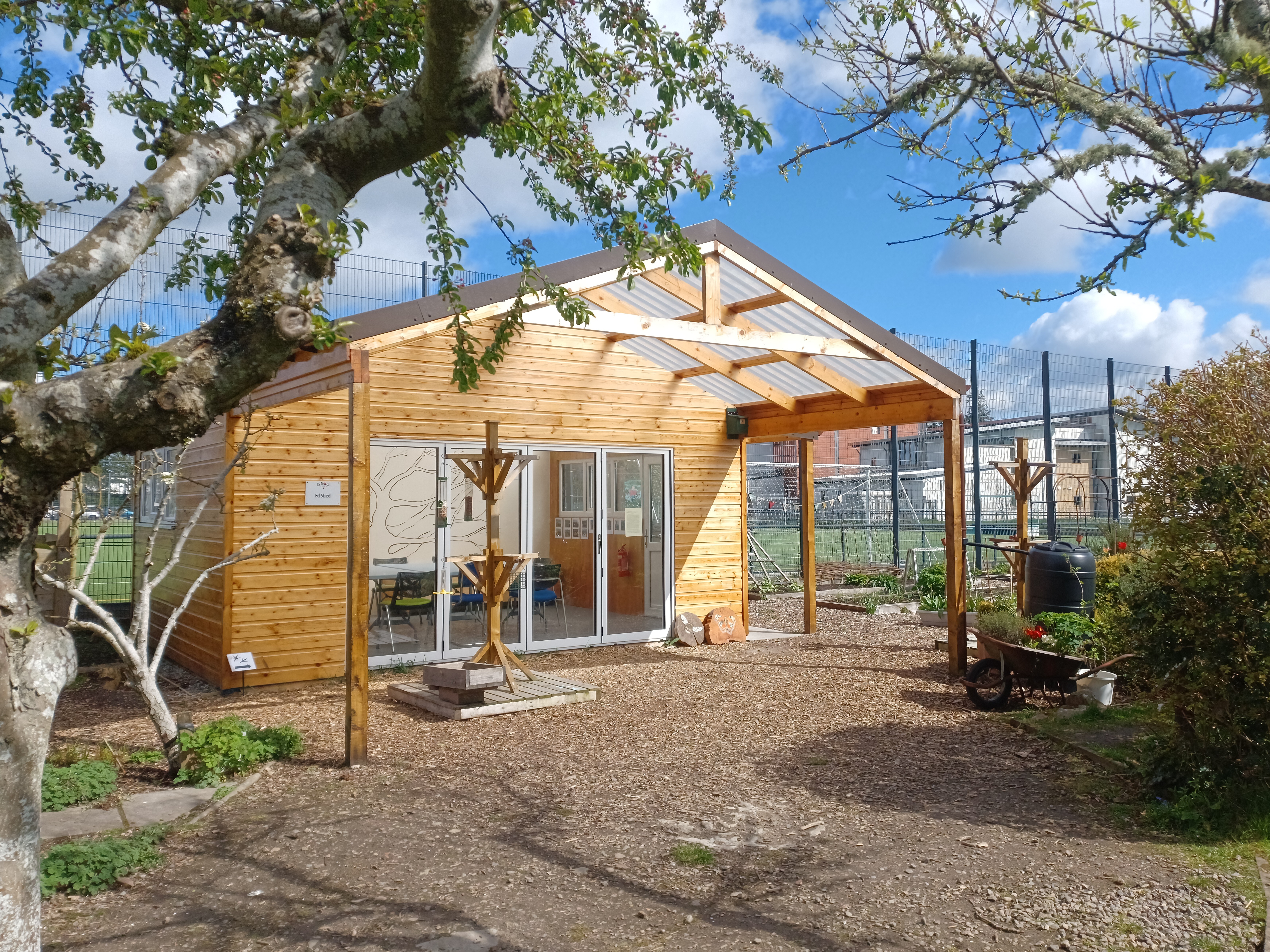 Looking through the branches of a tree onto an educational shed with patio doors providing a great outlook to the garden.