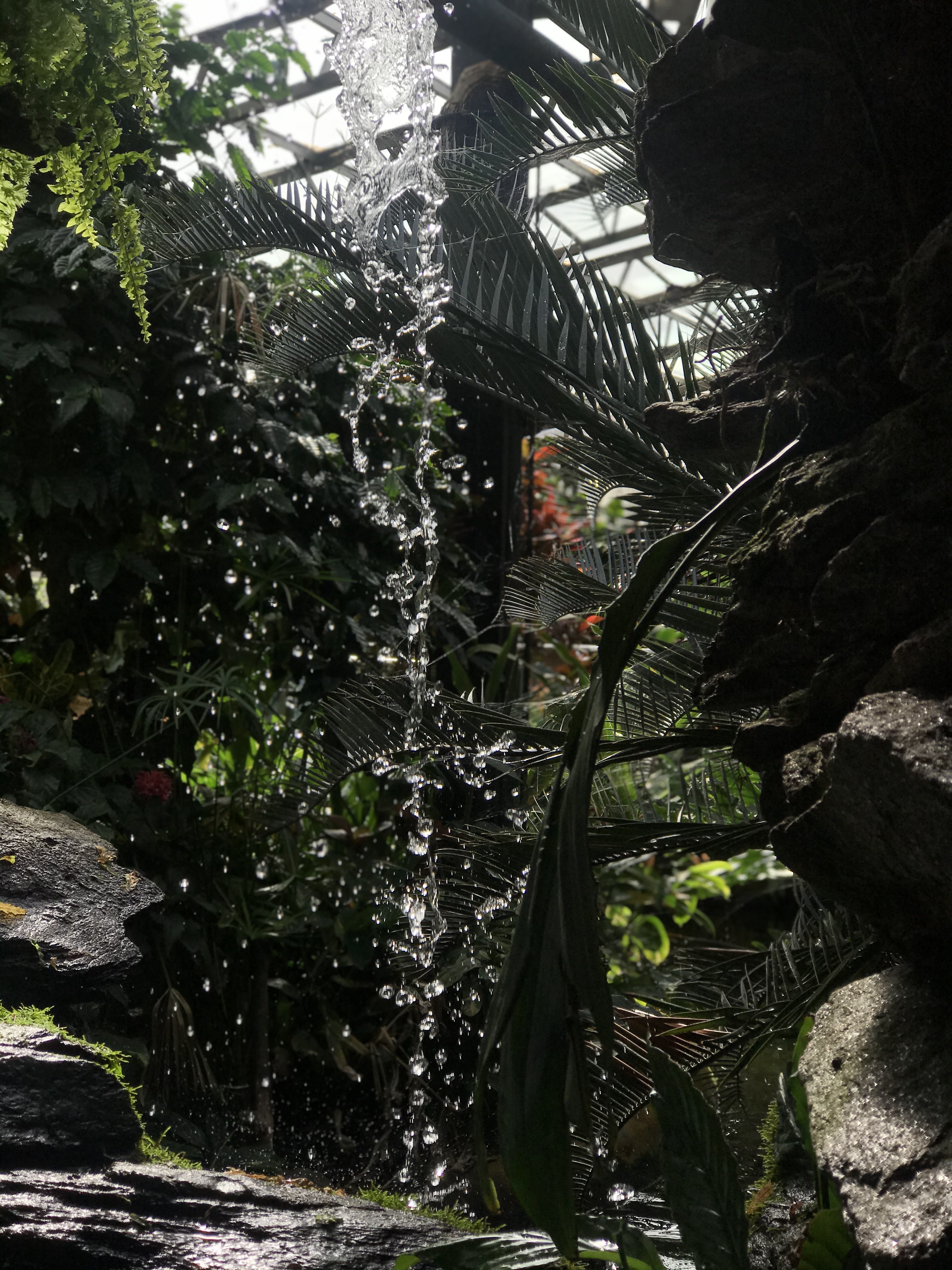A waterfall surrounded by rock and green planting in the background.
