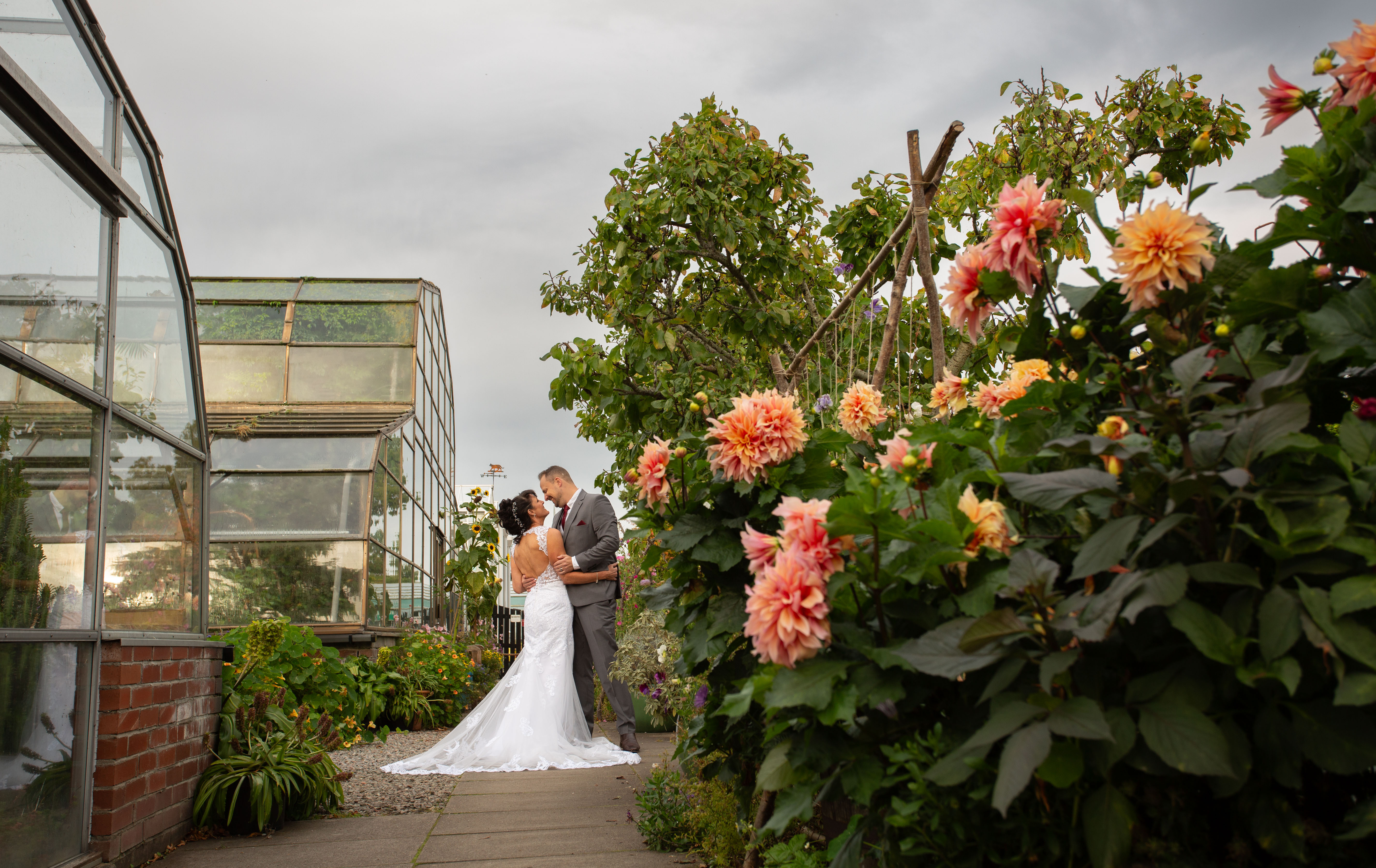 A bride and groom gazing into each other's eyes with orange dahlias in the foreground.