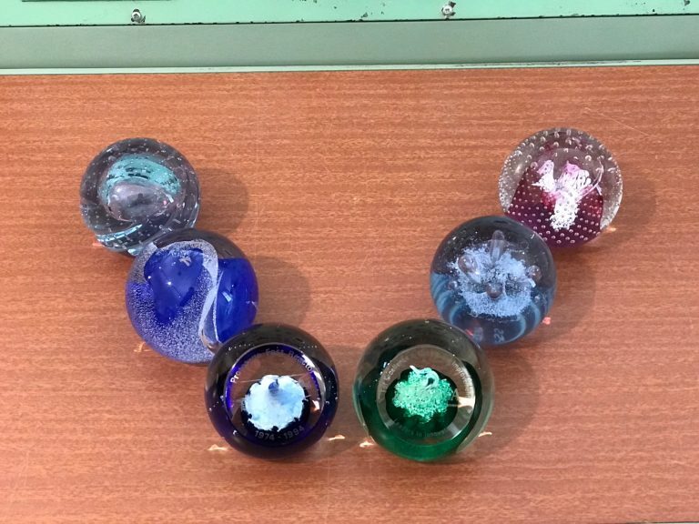 Decorative glass paperweights on a wooden surface, partially visible with colorful designs.