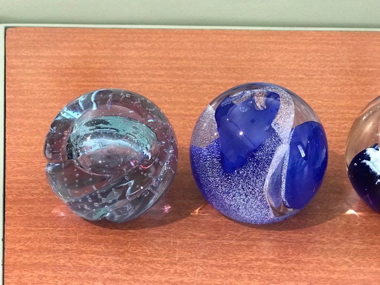 Two decorative glass paperweights with clear and blue designs on a wooden surface.