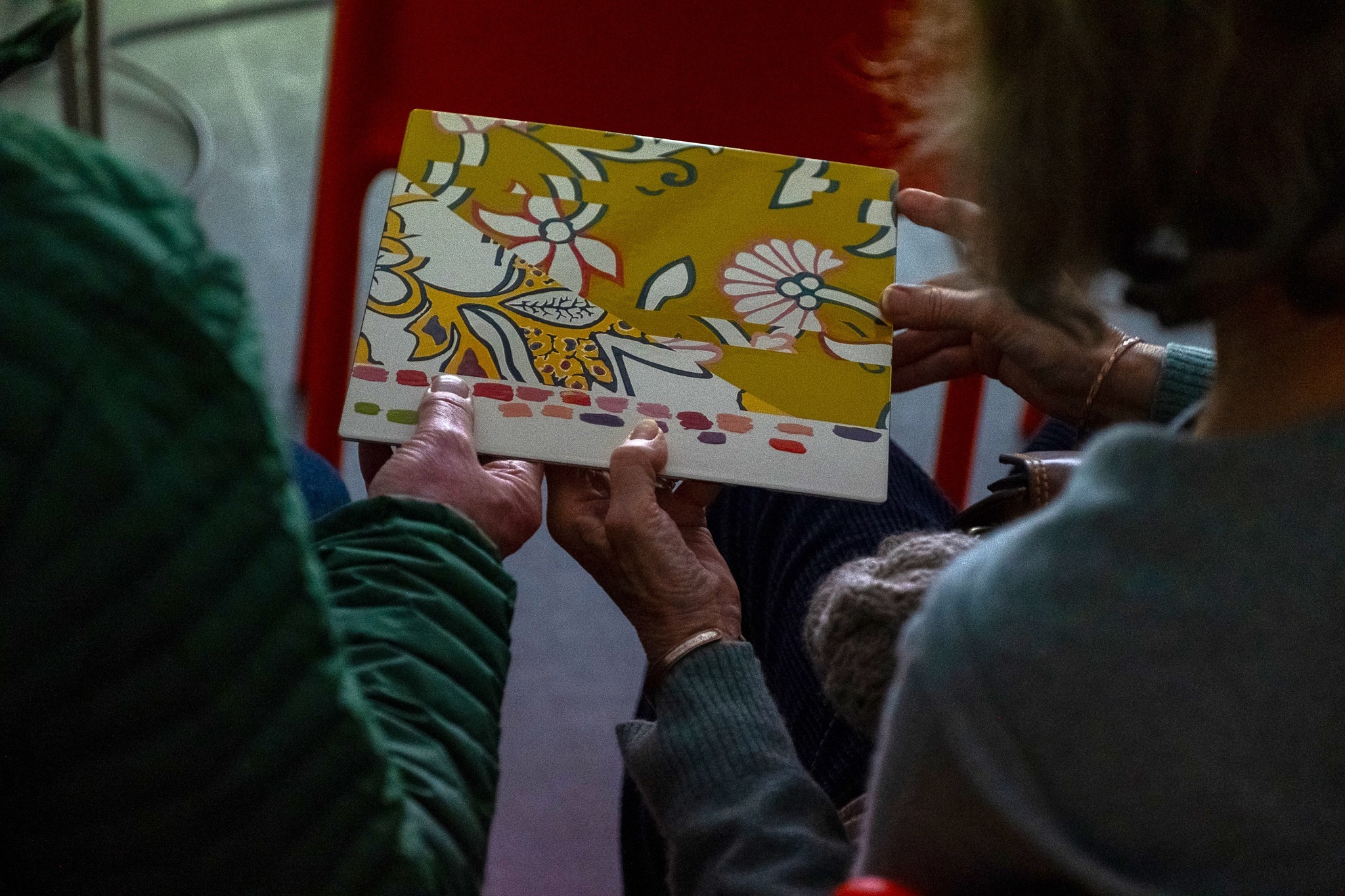 Two people holding a colourful patterned notebook.