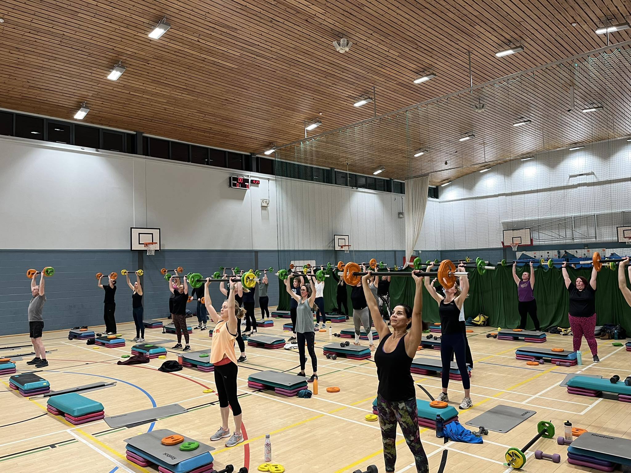 Sherand Esser Grant leading a Body Pump class at Craig MacLean Leisure Centre with a full room of participants lifting barbells overhead