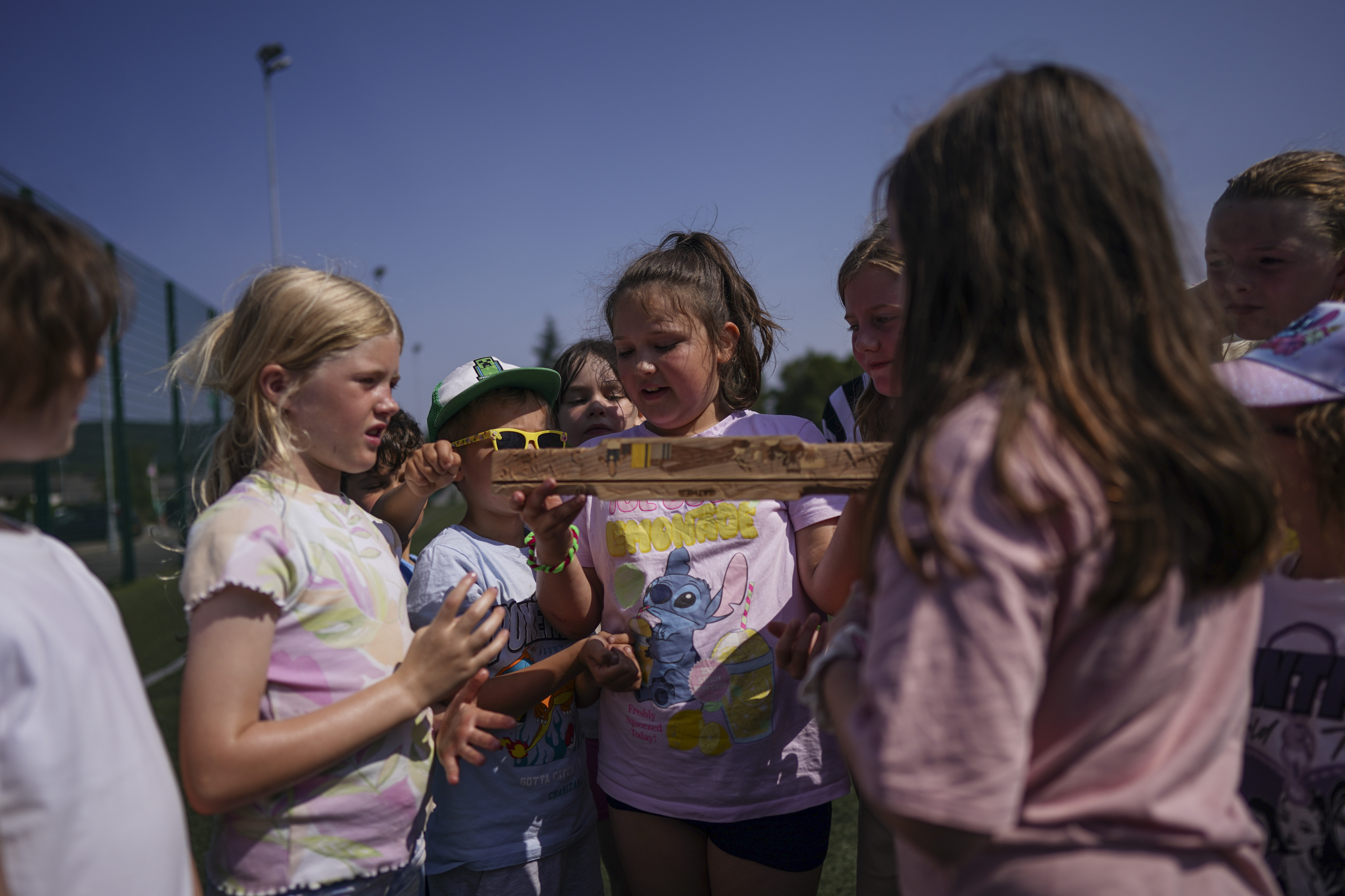 Group of children examining the carved King's Baton closely