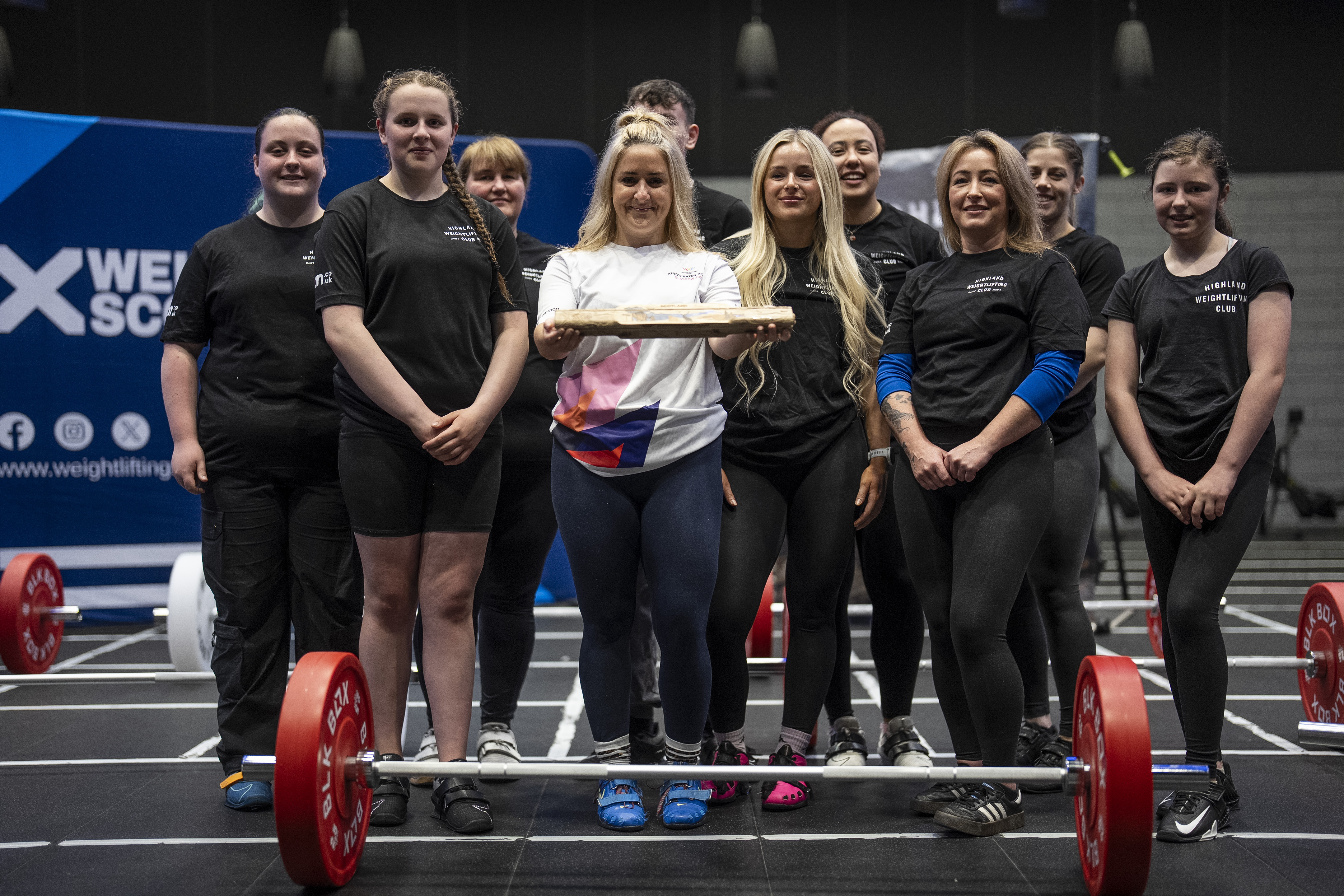 Highland Weightlifting Club team group photo holding the King's Baton, with Weightlifting Scotland banner