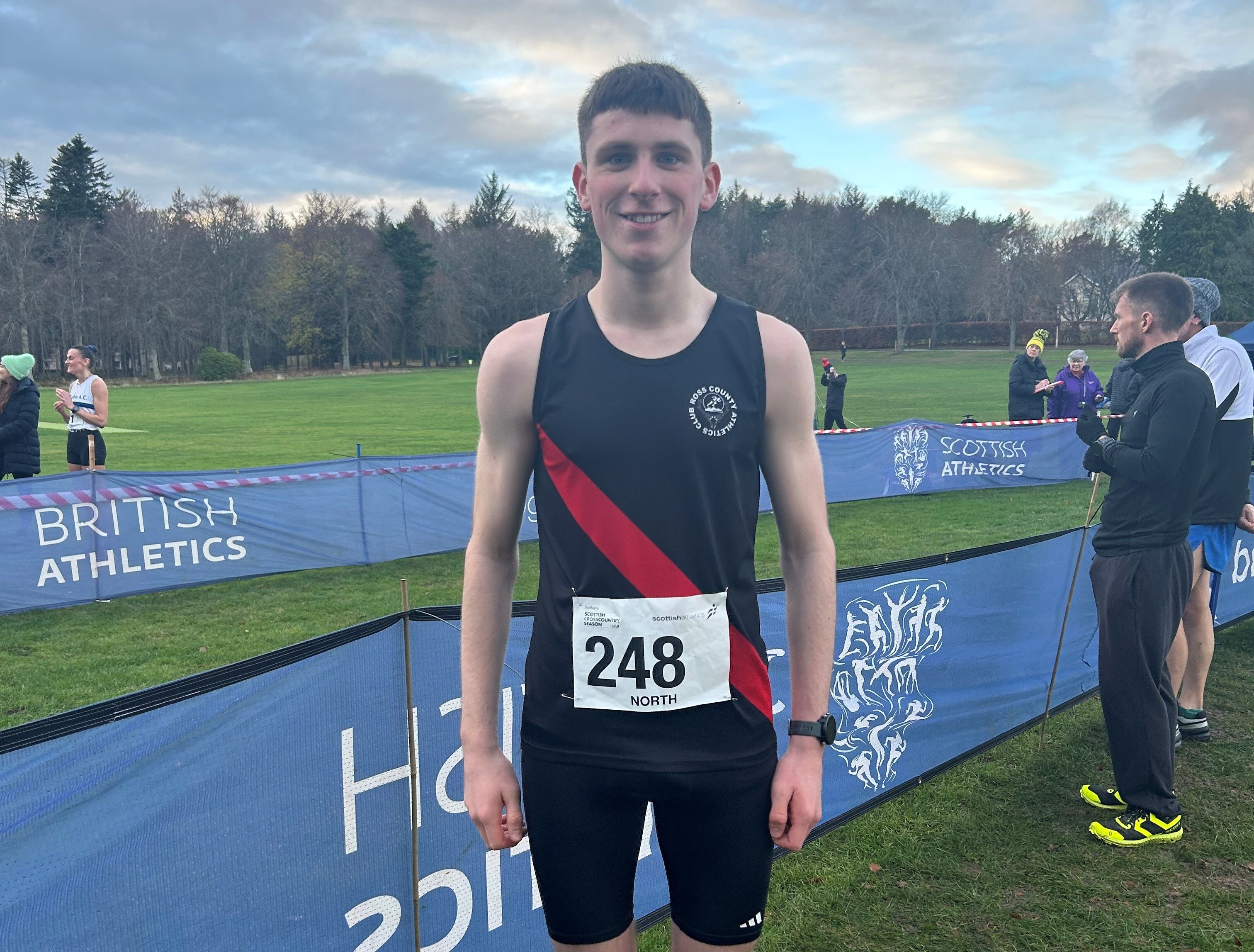 Billy Sutherland smiling at a Scottish Athletics cross country event, wearing race number 248
