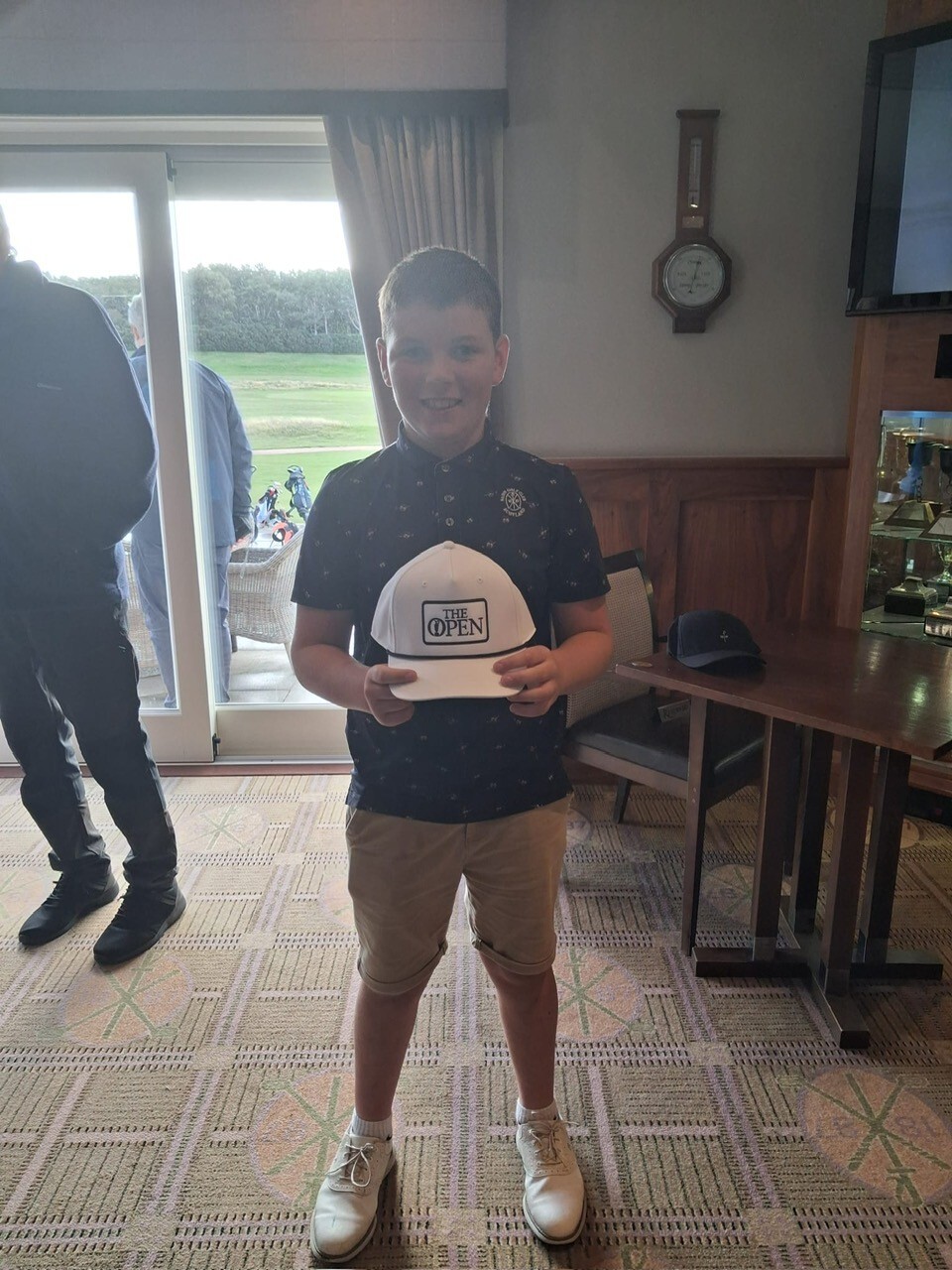 Young golfer holding a golf cap.