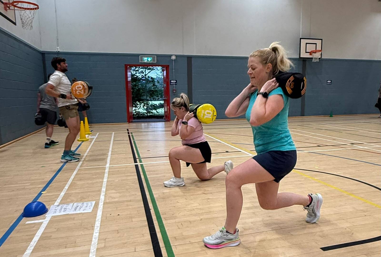 Women lunging with sandbags in class