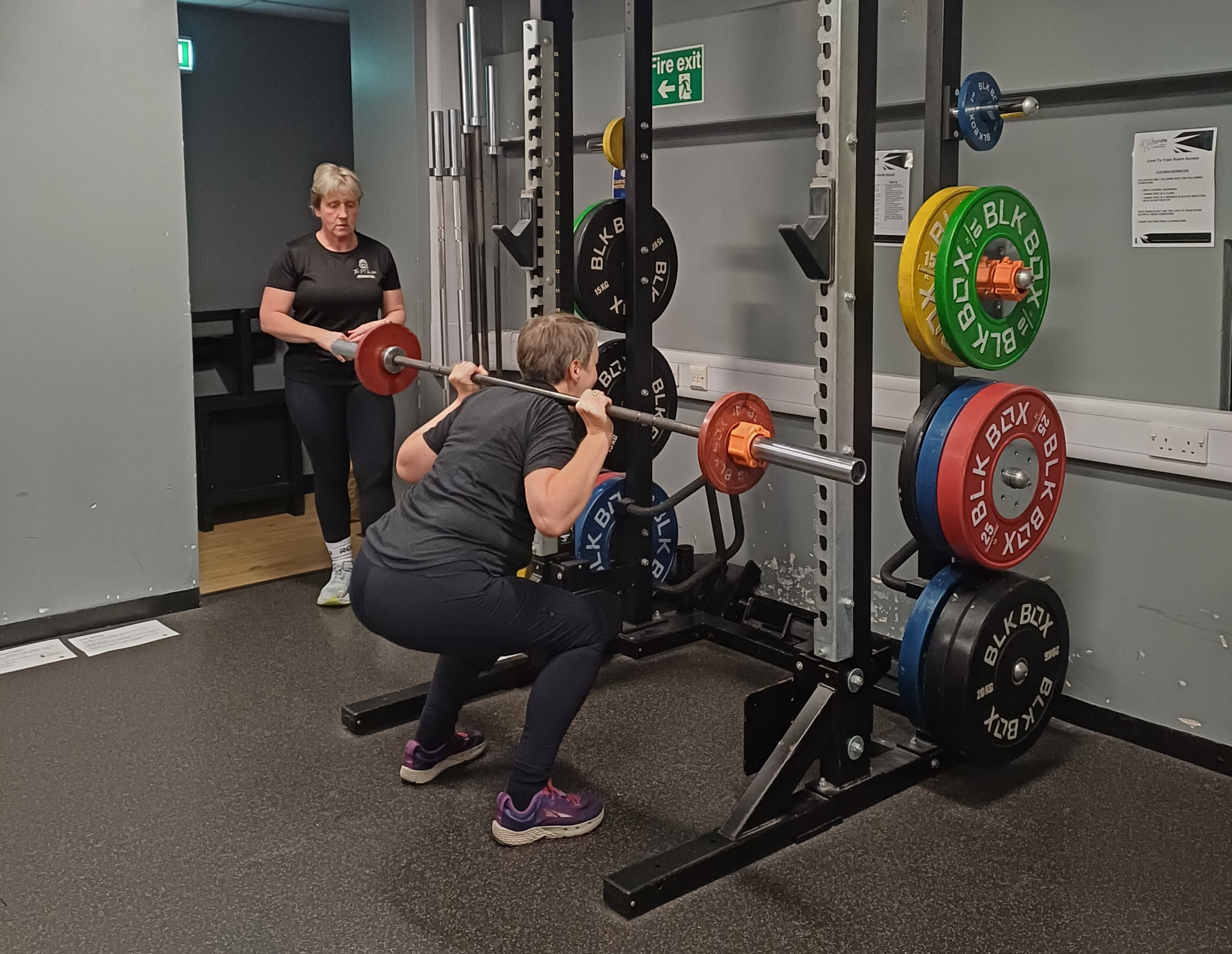 Cancer rehab class doing barbell squats with support