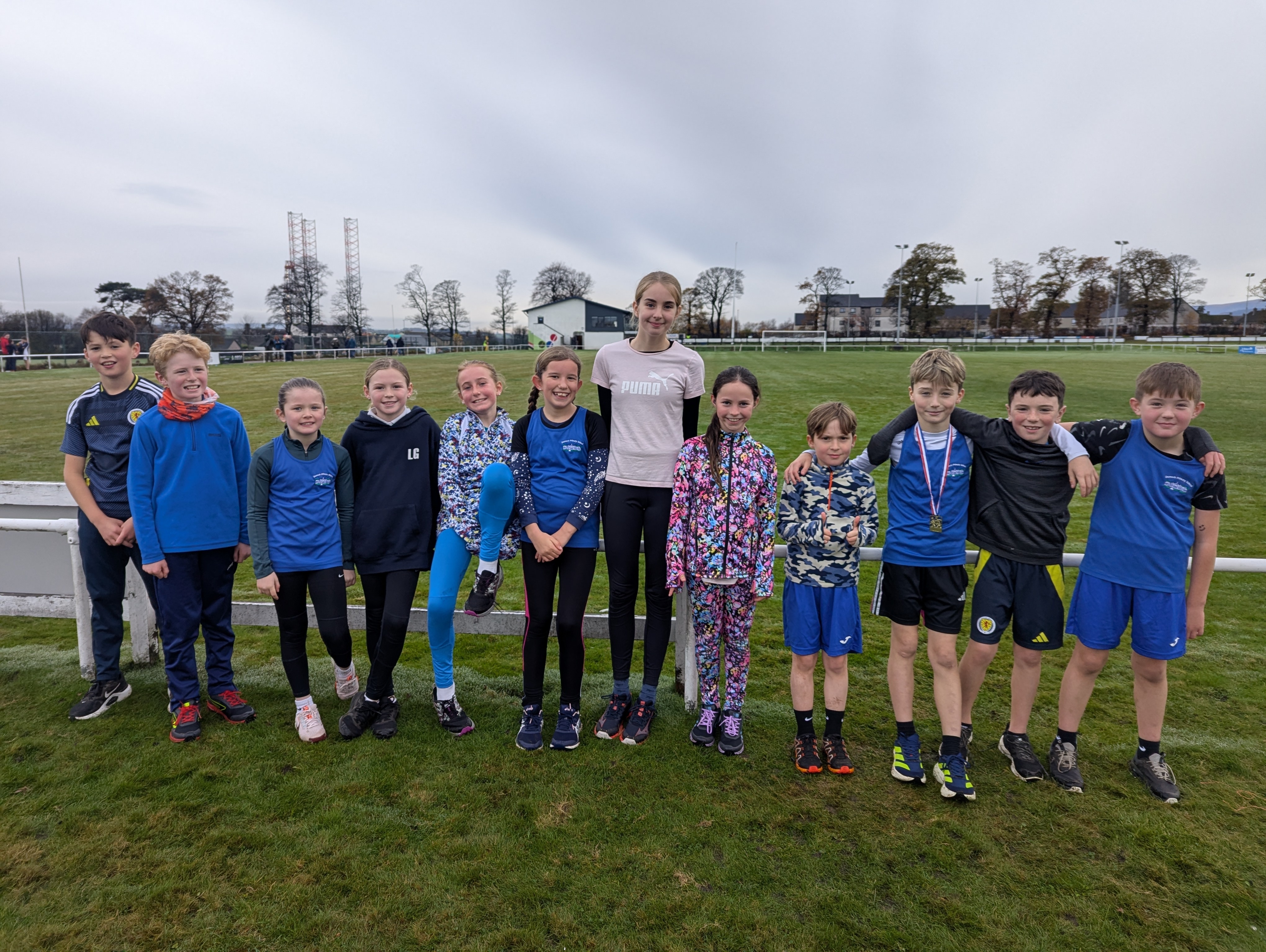 12 young people lined up wearing gym kit standing on a playing field.