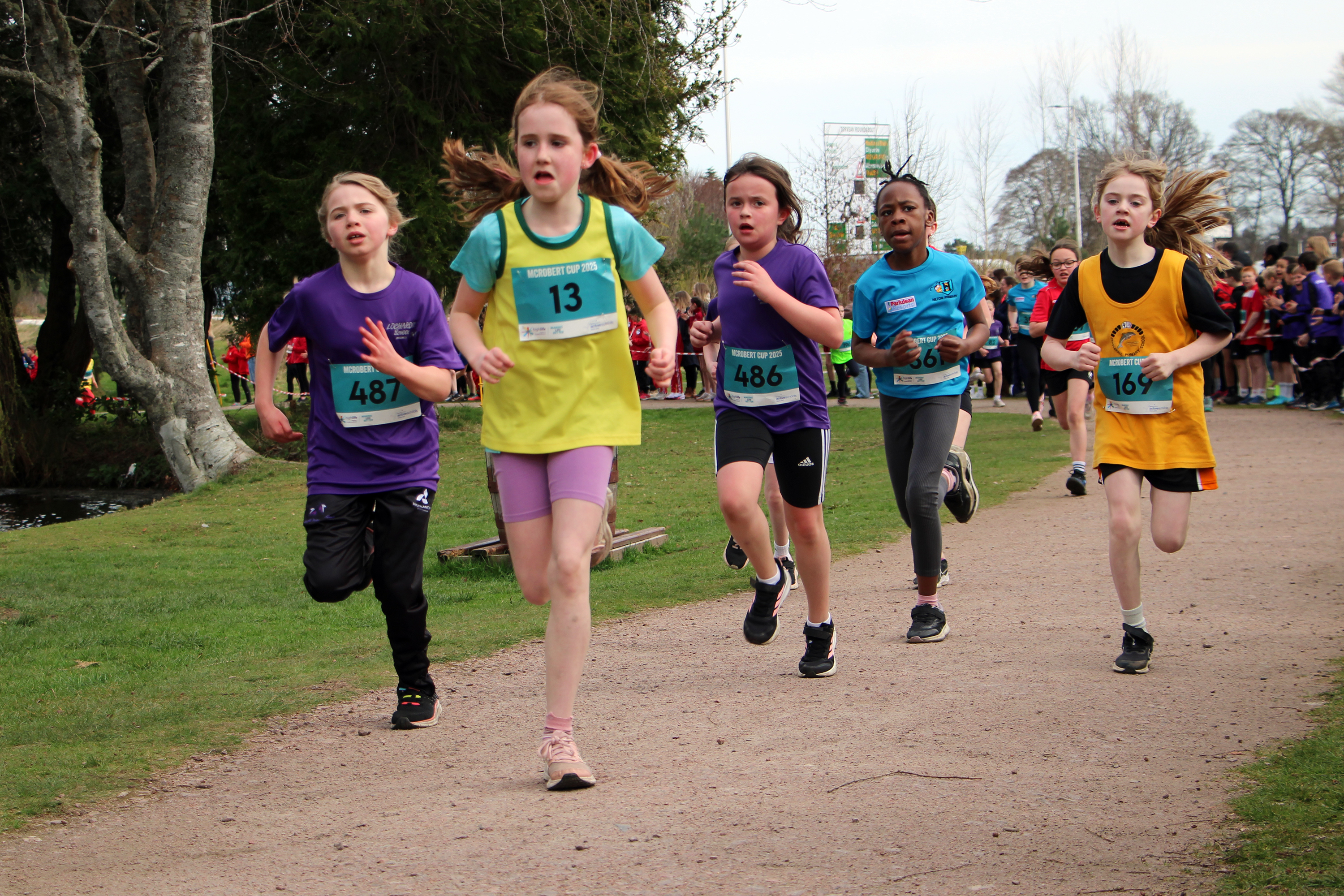 A group of primary school girls running a race in a park.