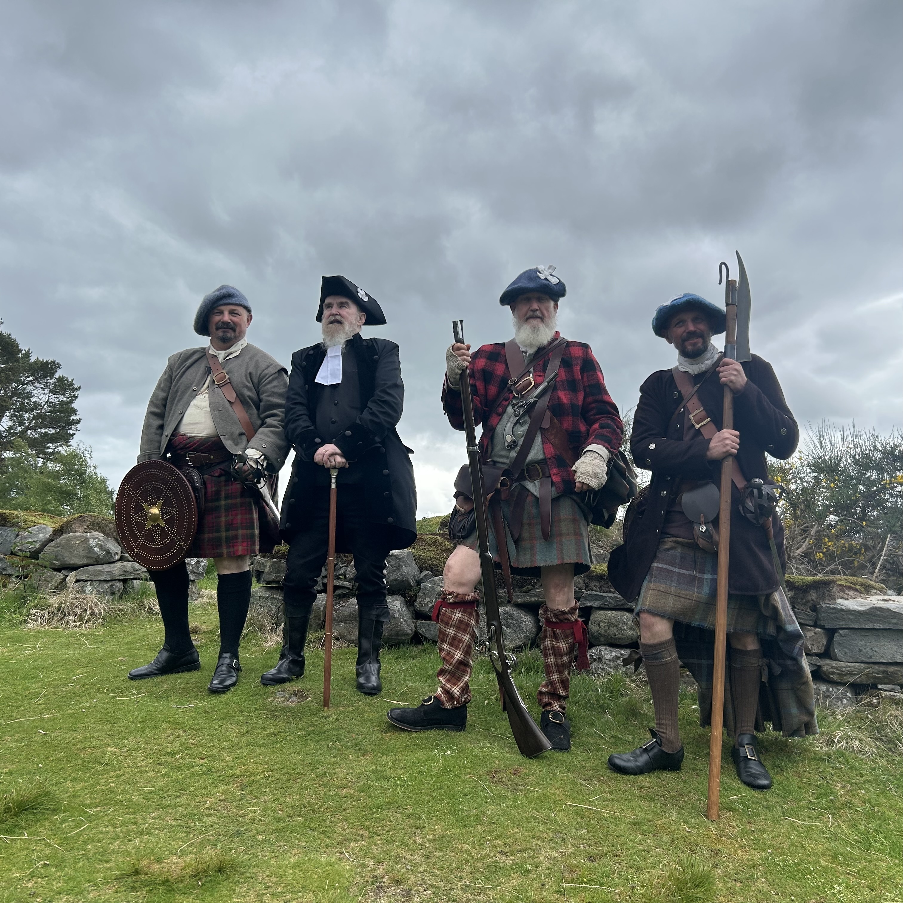 Four men in full 18th-century Highland costume with period weapons at Outlander Day, Highland Folk Museum