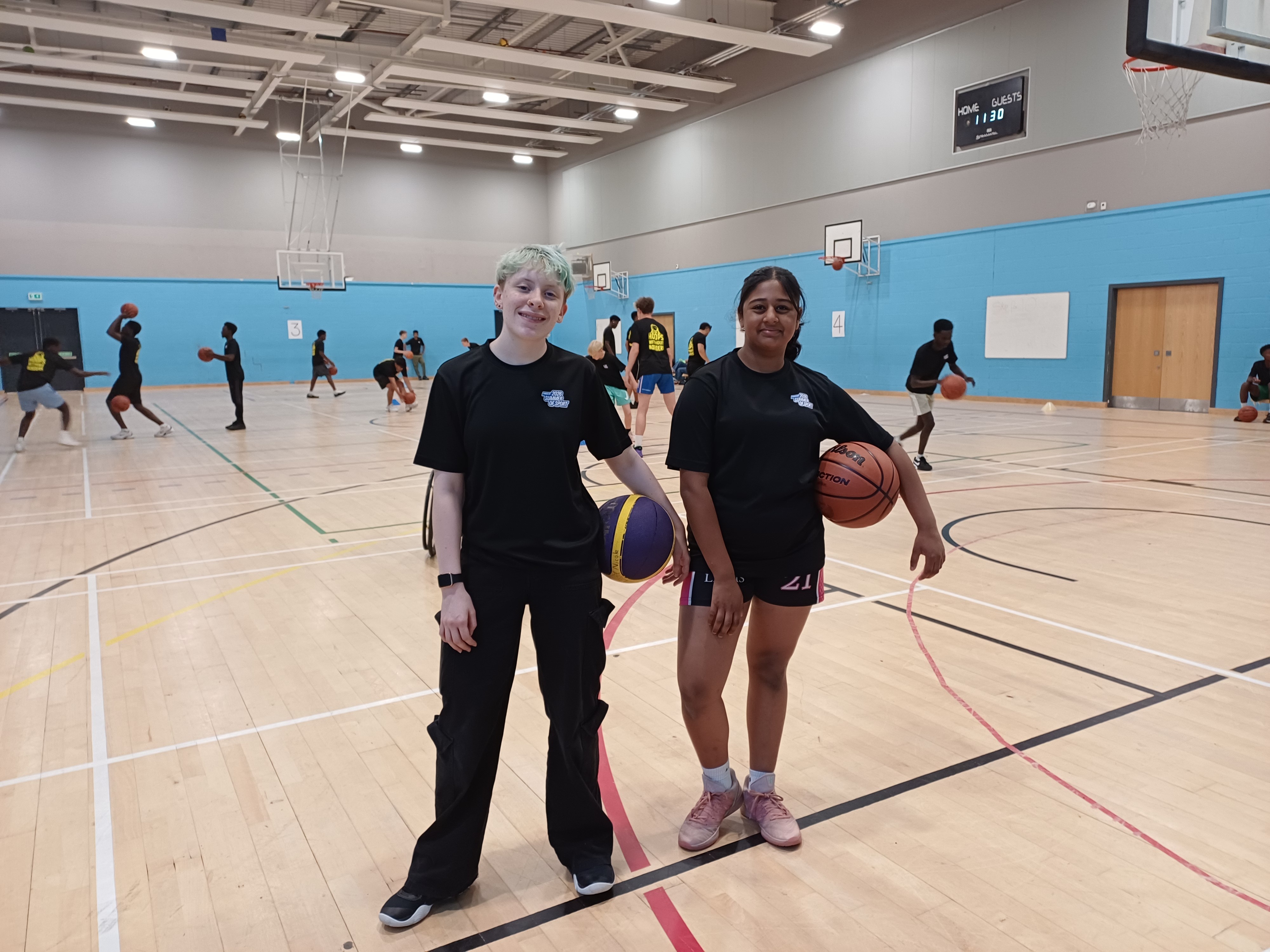 Two young women holding basketballs on the court
