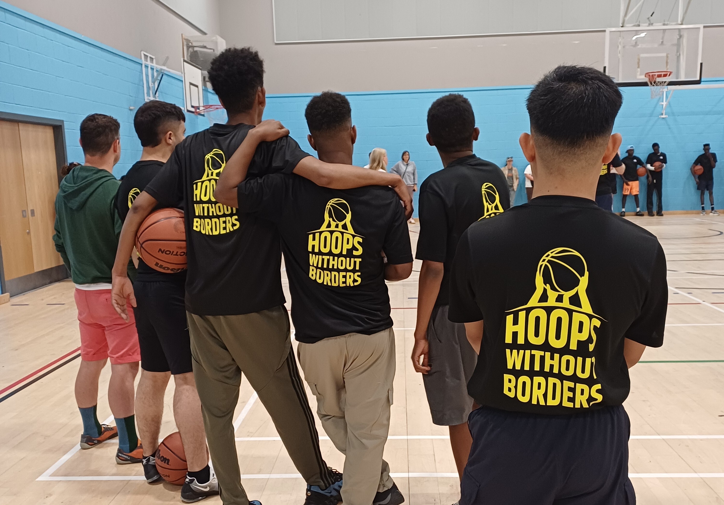 Young people in Hoops Without Borders shirts standing together