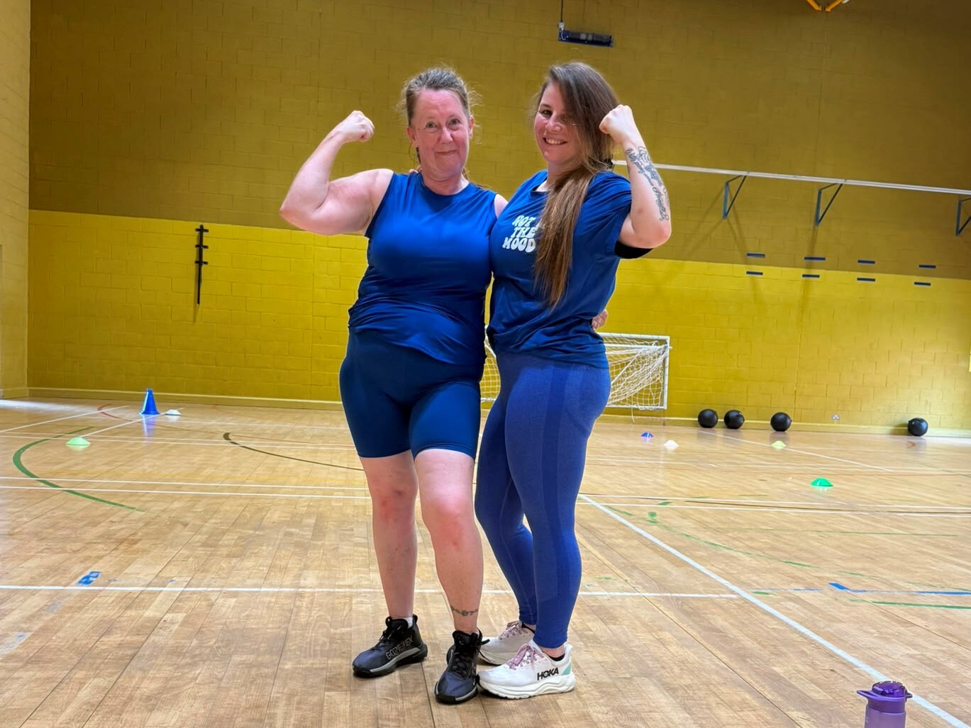 Two women flexing arms after class