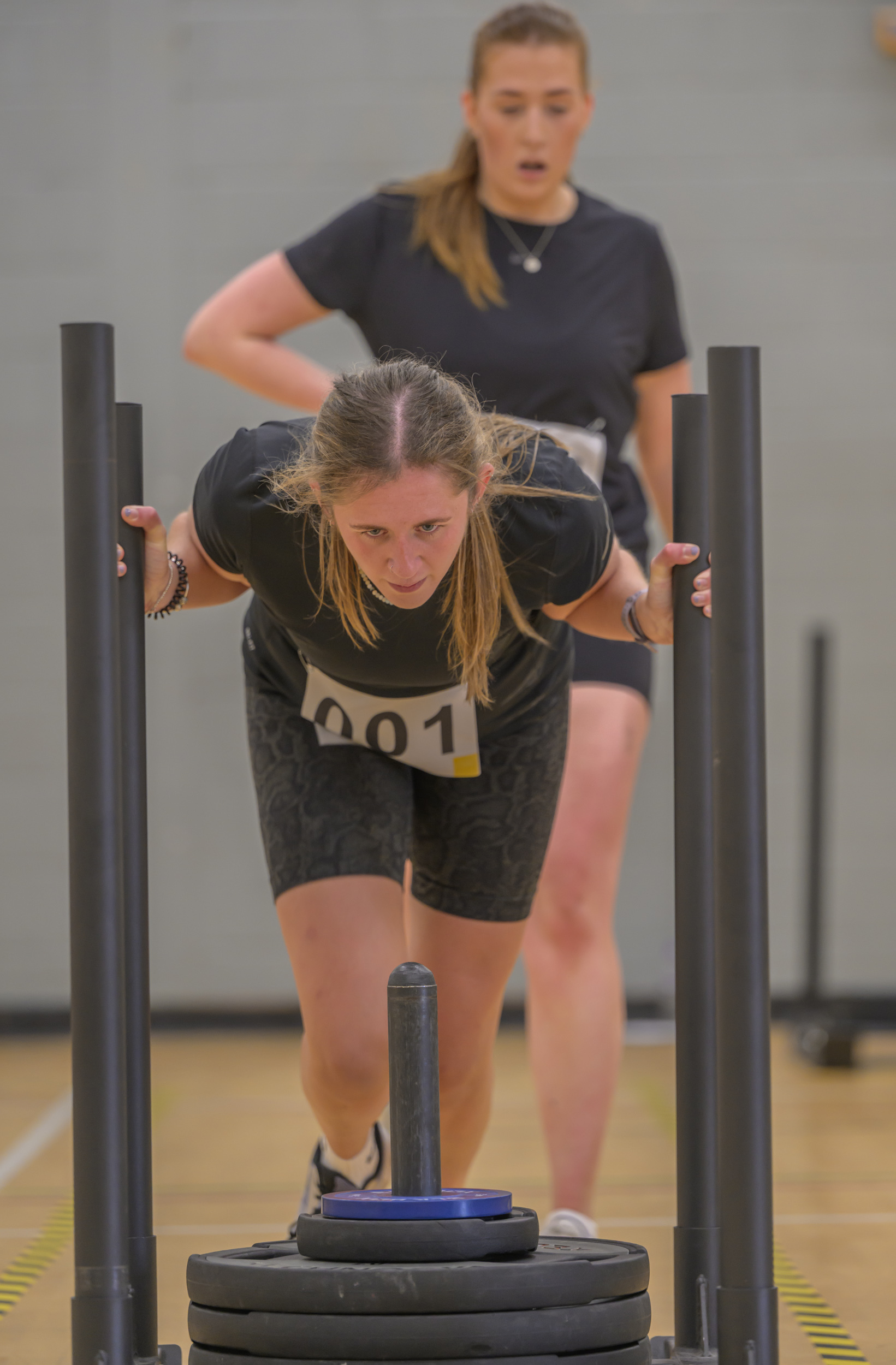 Woman pushing weighted sled at Lochaber HYROX Sim