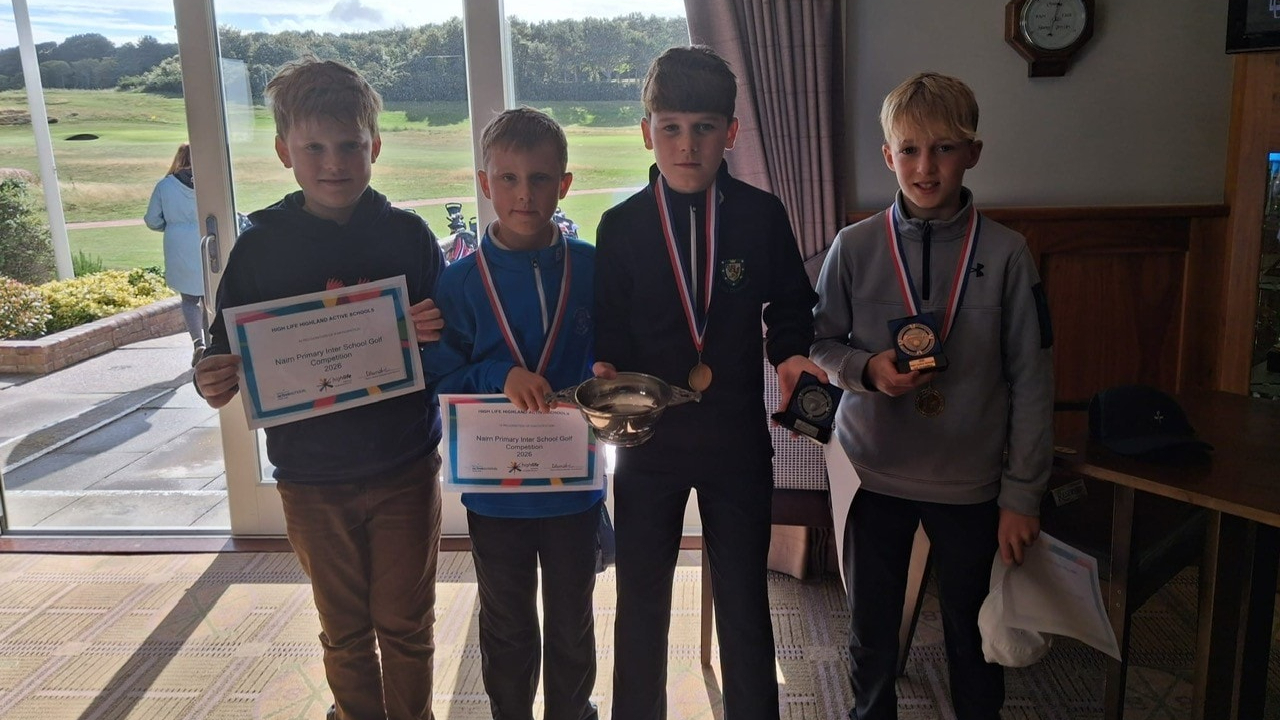 Four pupils with certificates, medals and a trophy in a golf clubhouse.