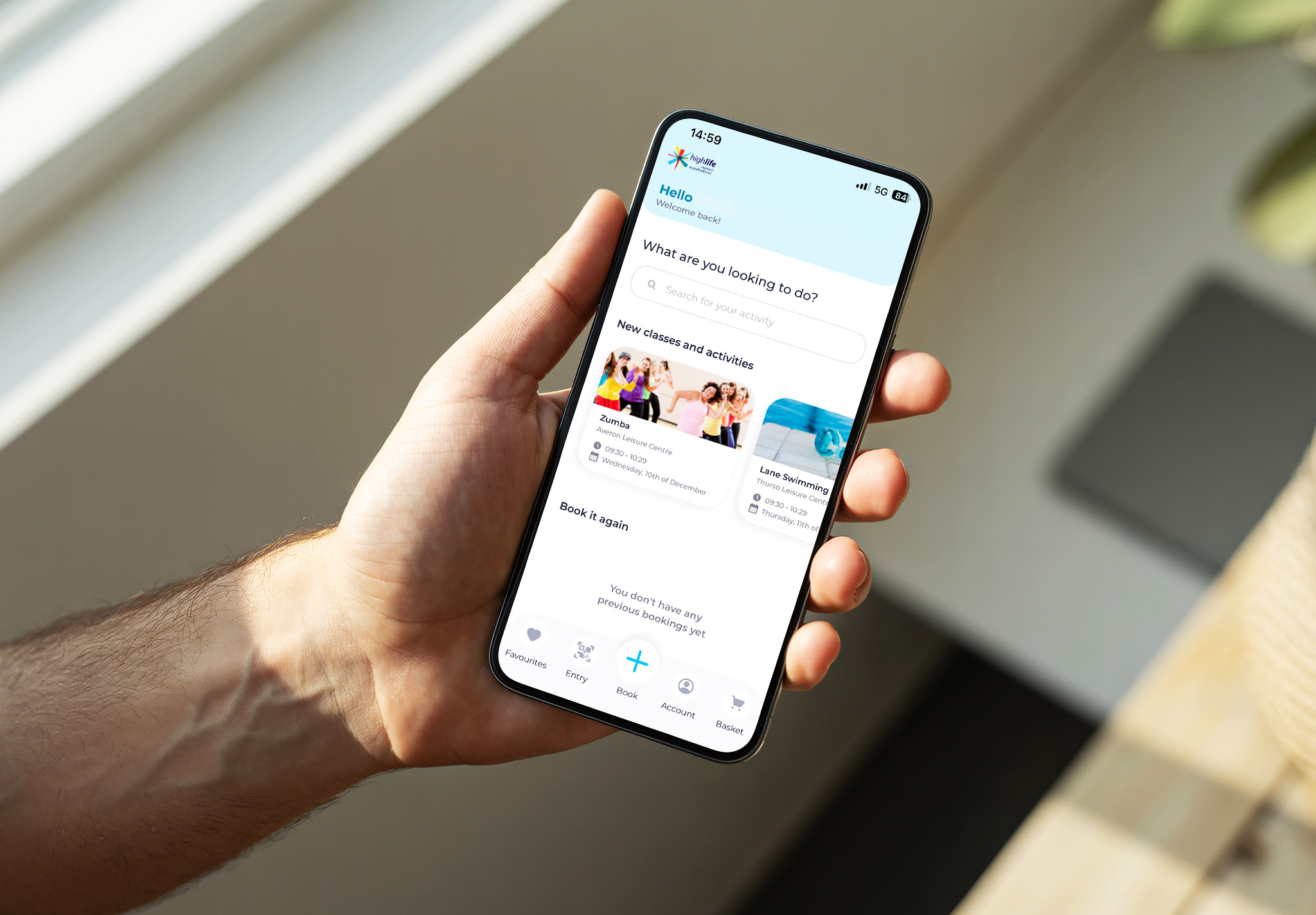 A mobile phone showing the HLH app on the screen being held by a man's hand.