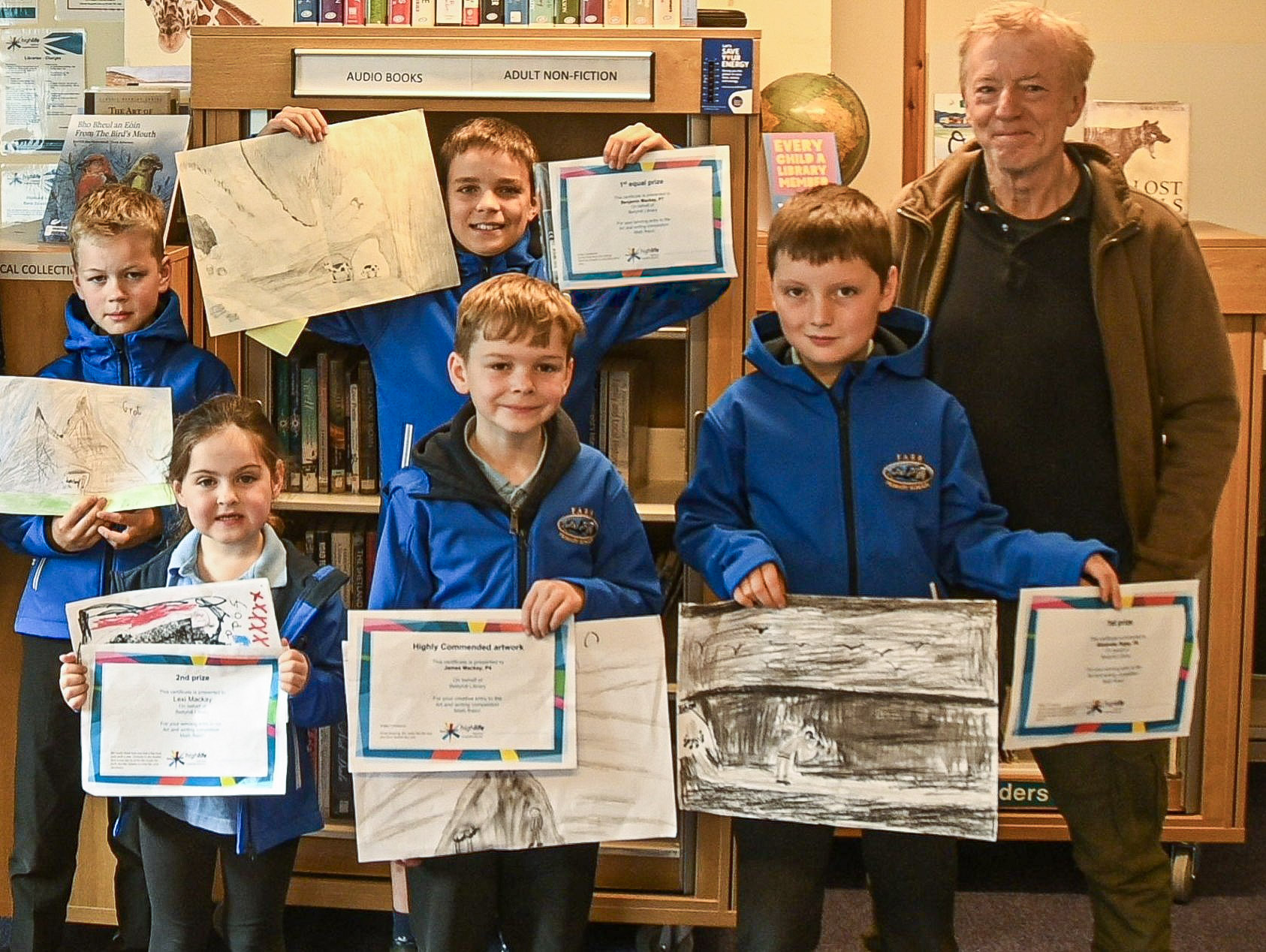 Prize-winning pupils from Farr Primary School holding their artwork and certificates at Bettyhill Library, with judge and artist Jim Wright