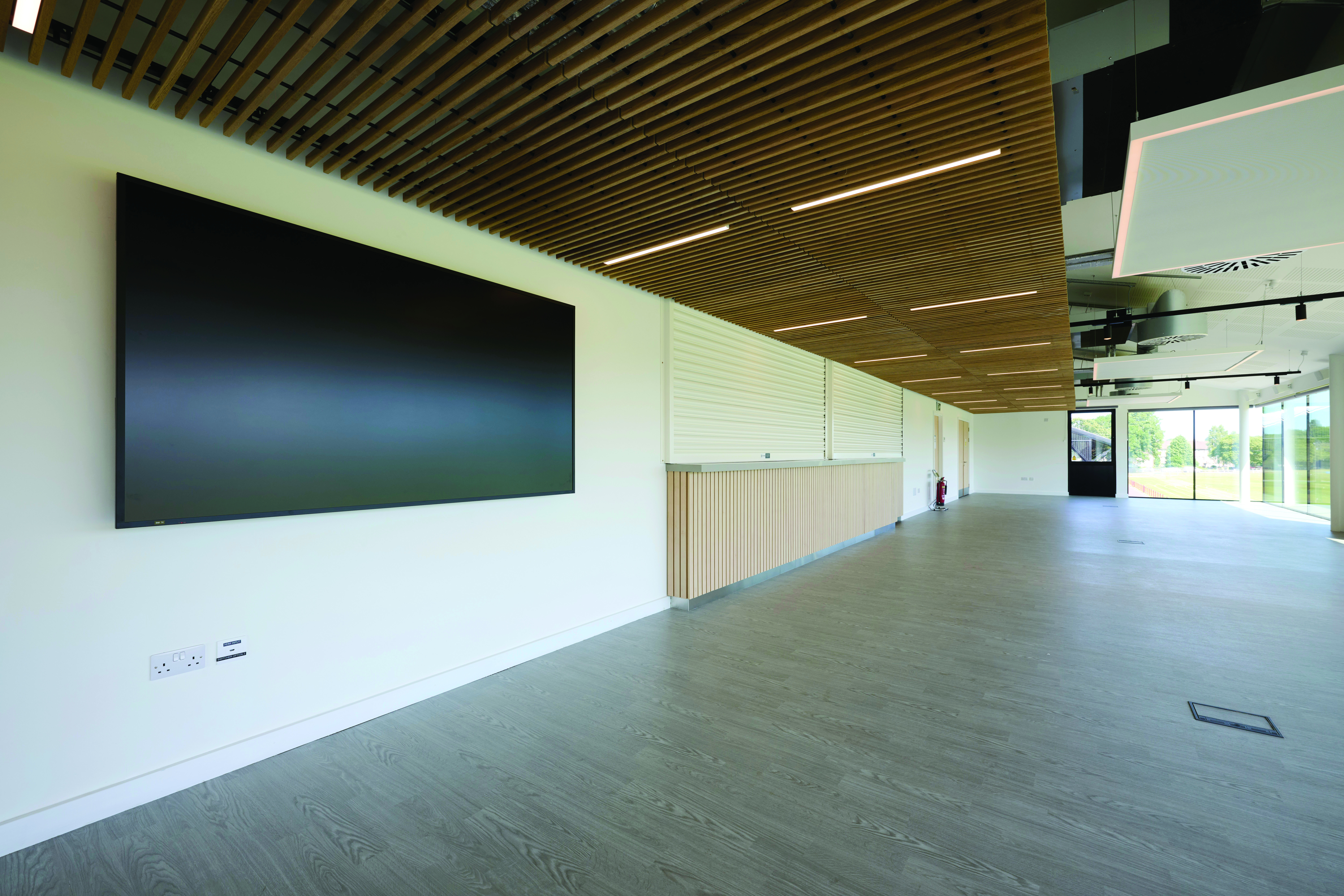 Spacious room with linoleum, floor to ceiling windows and a wall-mounted TV.