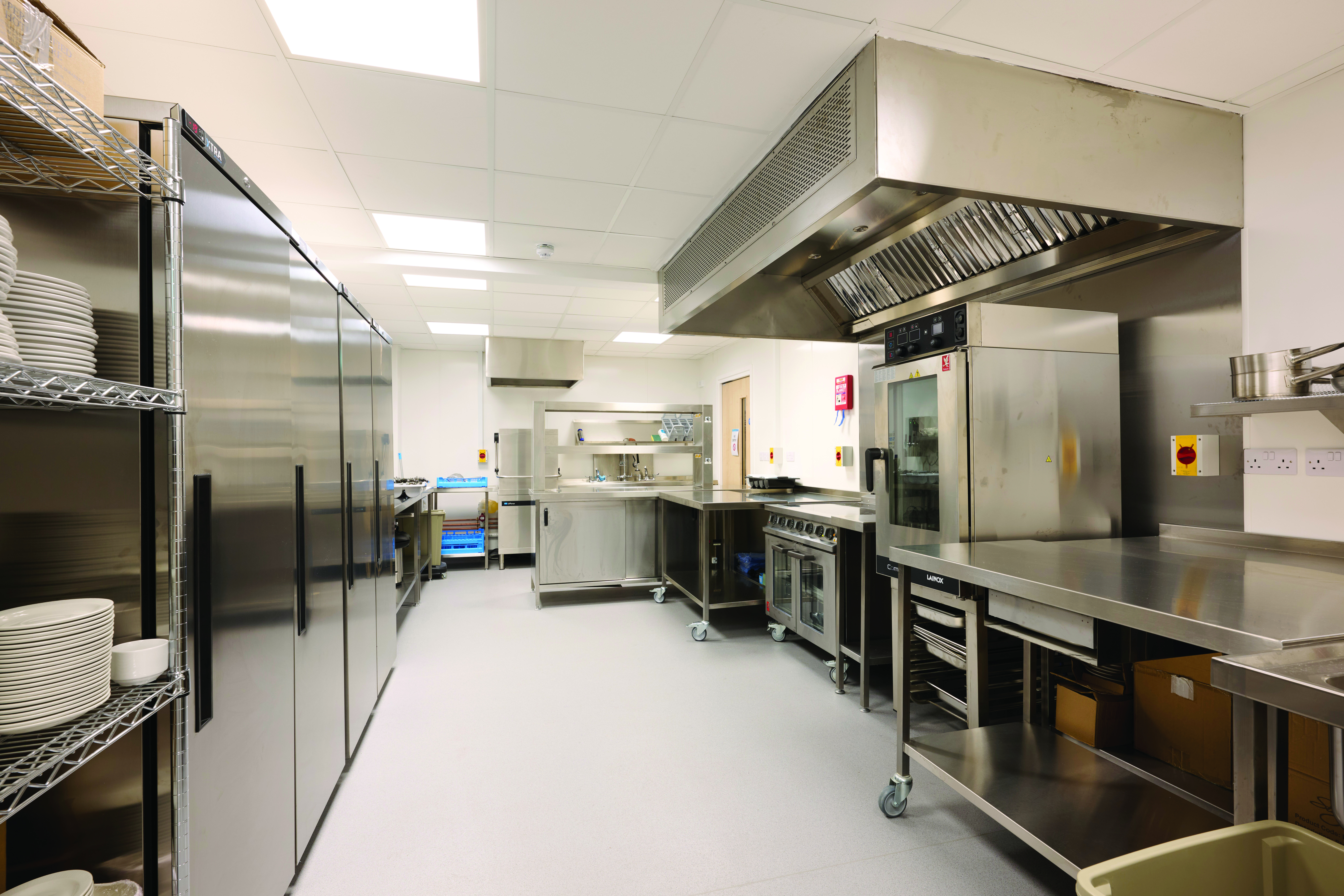 A fully equipped catering kitchen featuring stainless steel appliances, units, and work surfaces, complete with industrial-sized ovens and available crockery for use.
