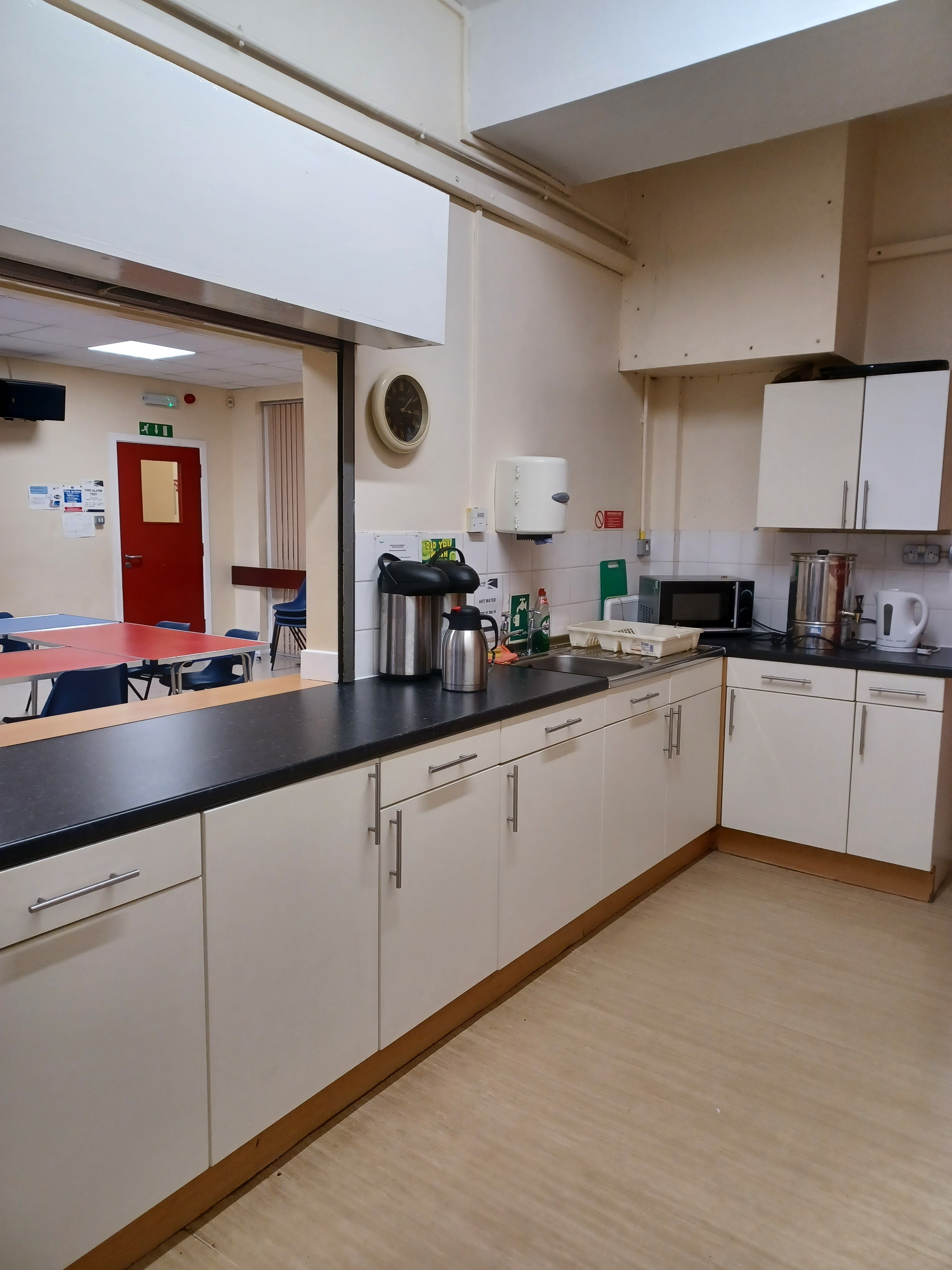The kitchen includes a sink, microwave, hot water urn and kettles, complemented by a serving hatch.