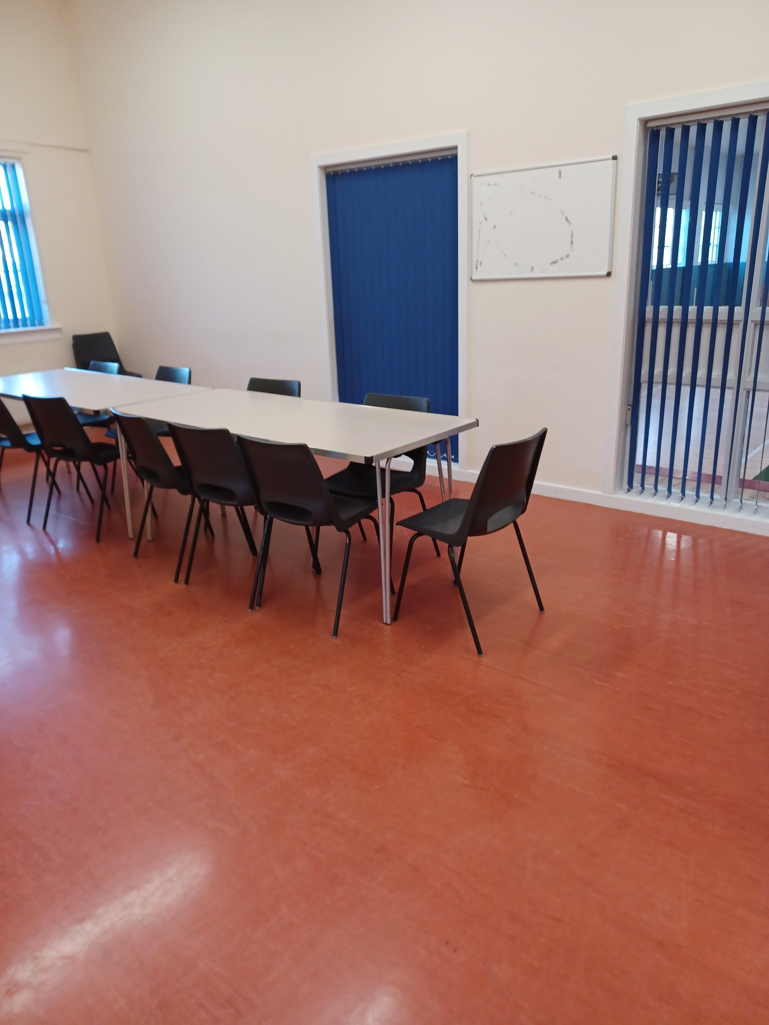 A well-lit room with linoleum flooring, designed as a meeting space, complete with surrounding chairs.