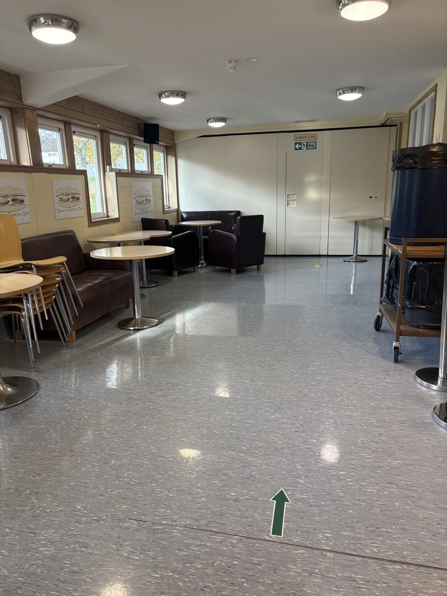 The Gordon Suite opens into a café area, featuring circular tables accompanied by a variety of seating options that include both hard and comfortable choices.