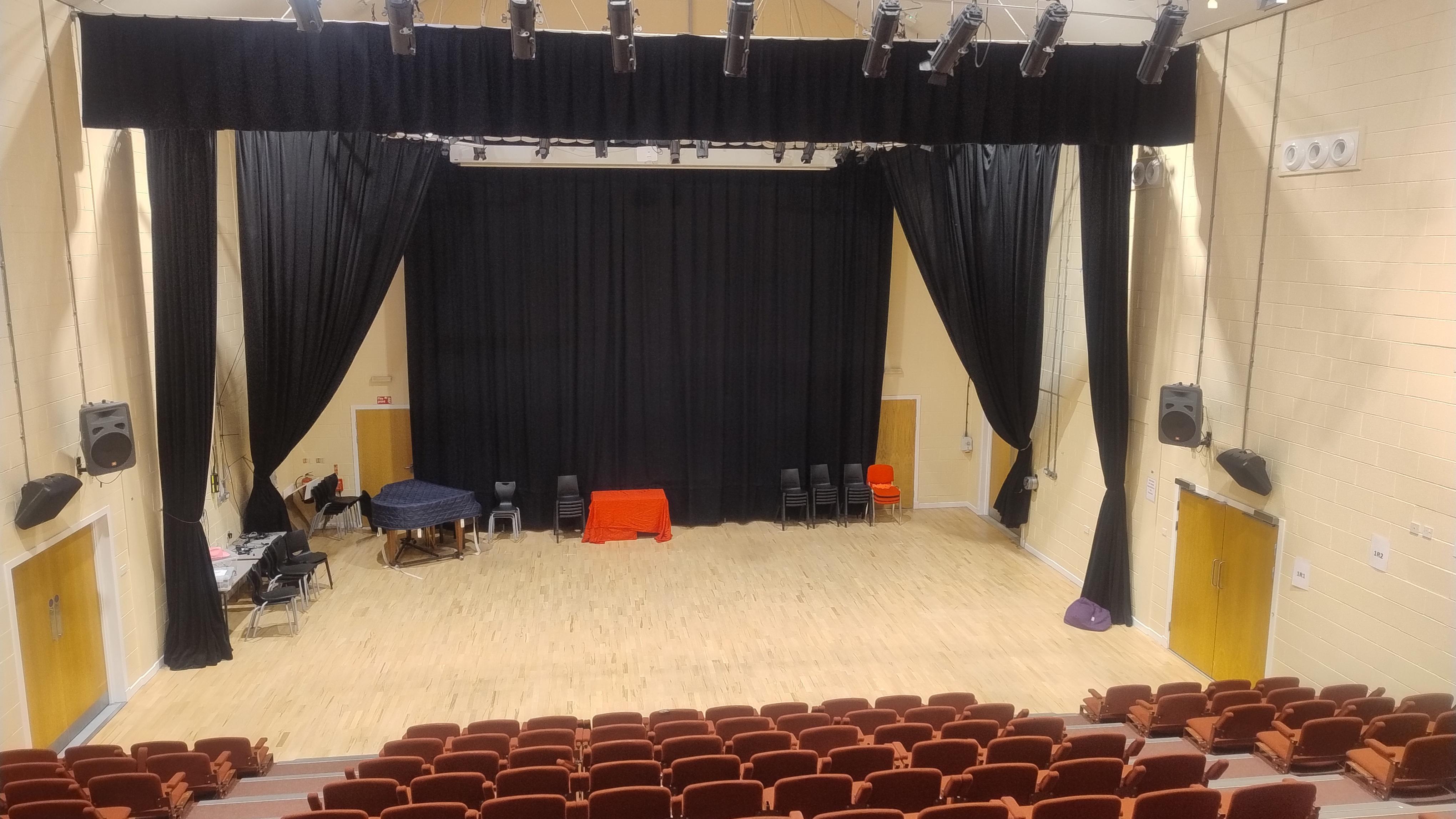 Theatre hall with a curtained area to create a stage and tiered seating.